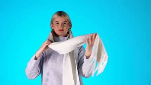 Young Blonde Woman Feeling Cold, Shivering, Blowing and Rubs Hands To Warm Up, Colorful Studio Shot