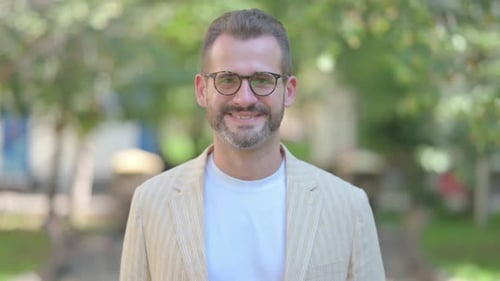 Smiling Man Wearing Glasses and a Beige Blazer