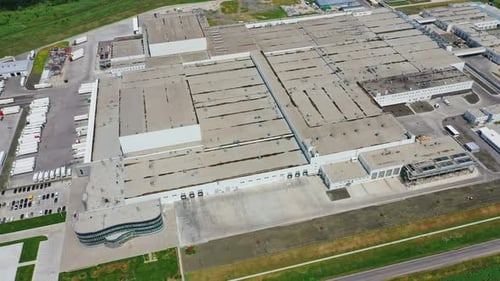 Industrial plant on green field. Modern manufacturing with car parking.