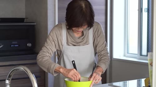 Senior Woman Mixes Ingredients in Kitchen Bowl