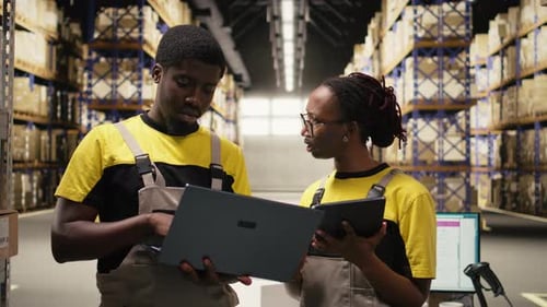 Large Business Warehouse Staff Handling Order Fulfillment with Laptop Data