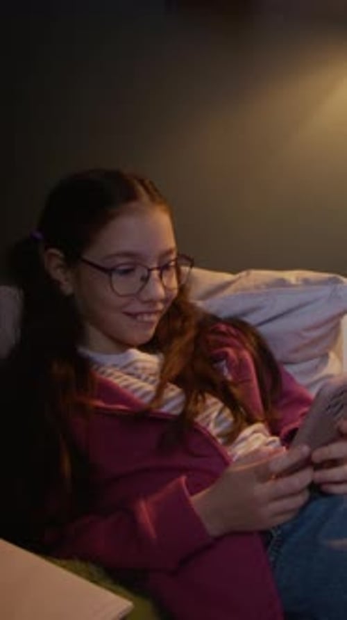 Girl with Glasses Using Smartphone on Couch at Home