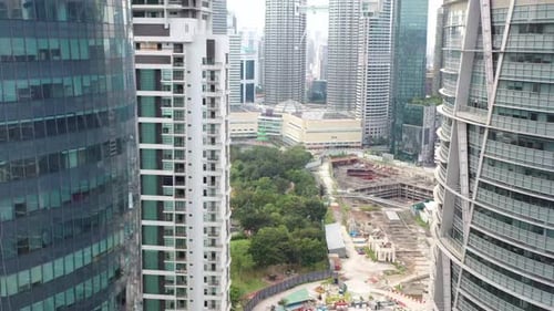Cinematic drone fly through downtown skyscrapers, tilt up reveals famous landmark petronas klcc twin