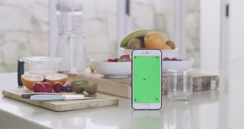 Closeup of a phone with a green screen and fresh fruit in the background