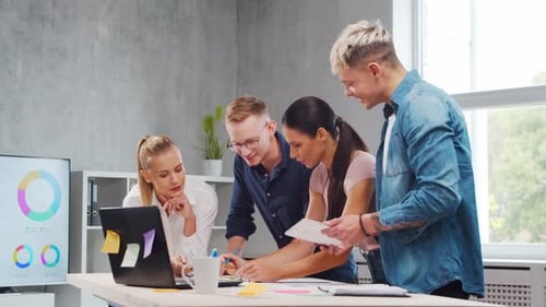 Team of Young Startupers is Working at the Table in the Office Discussing the Strategy and