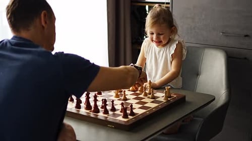 Father and Daughter Play Chess Game Indoors
