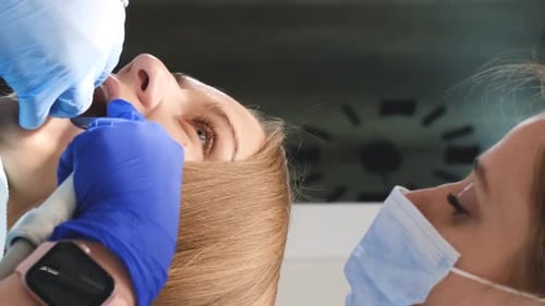 Dentist Treating Patient with Instruments in Dental Office