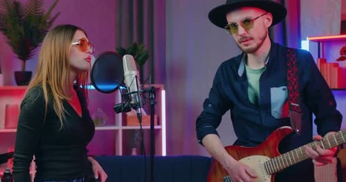 Music band of creative woman singer and man guitarist which recording song in home studio in the eve