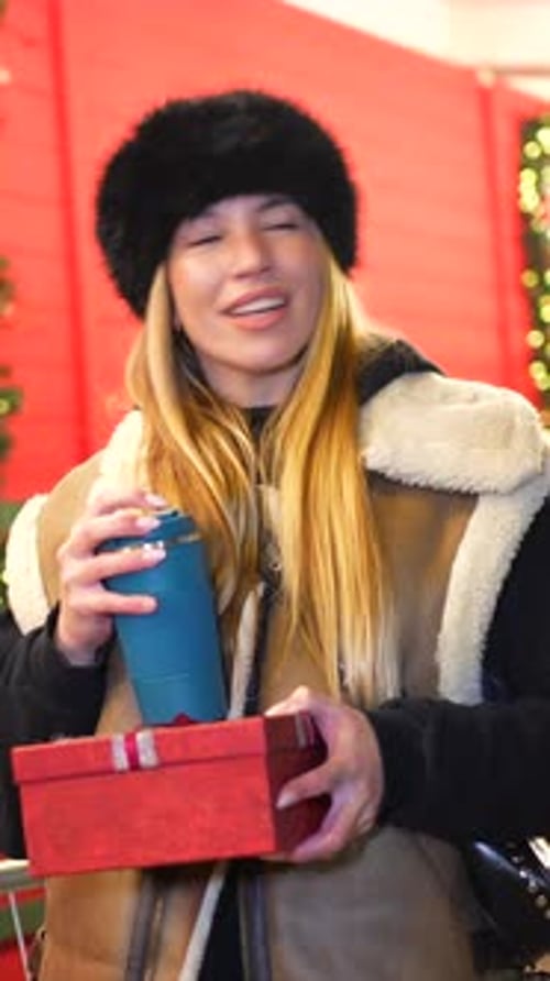 Woman Drinking Hot Beverage and Holding Christmas Gift