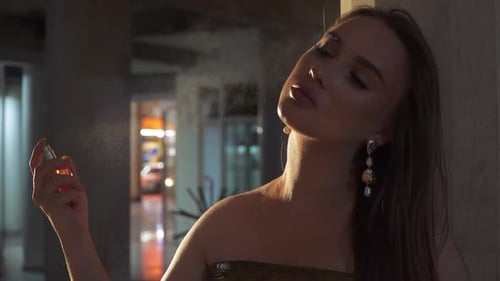 Elegant Woman Sprays Perfume in Urban Setting