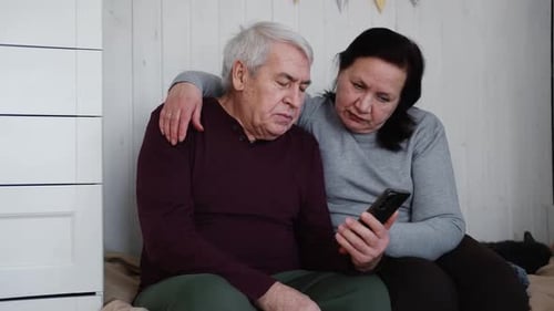 Senior Couple Uses Smartphone Together Indoors