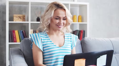 Young and Attractive Woman Works at Home Using Laptop Computer Freelancer or Student on the Couch