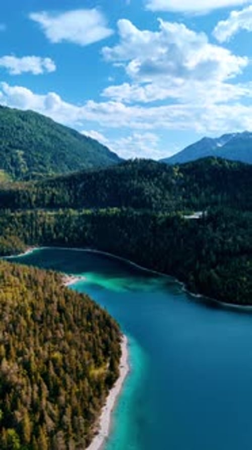 Turquoise lake in the mountainous area. Evergreen forests cover the rocks around.