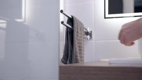 Hand Taking Gray Towel in Modern Bathroom
