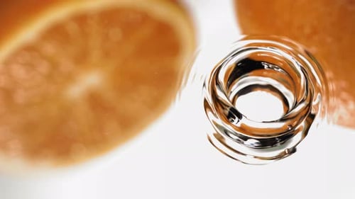 Makroaufnahme von Wassertropfen, die im Spiegel auf eine Orange fallen, in Superzeitlupe