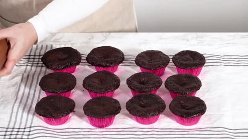 Piping Chocolate Ganache Frosting on Top of Chocolate Cupcakes