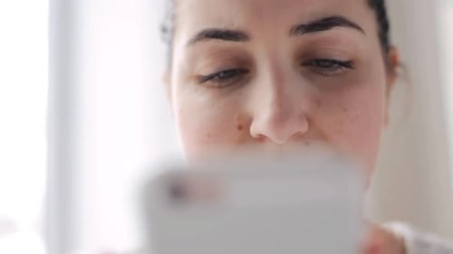 Woman Smiling Looking at Phone Screen Indoors