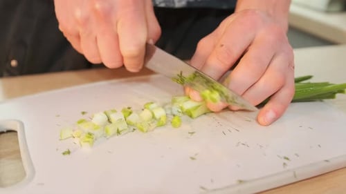 Close-up of male hands chopping green onions on a cutting board