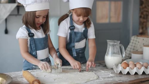 Zwei Kinder in weißer Kochuniform backen in der Küche Formen aus Teig