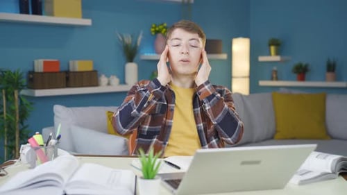 Tired Young Adult Using Laptop At Desk