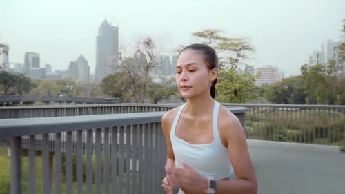 Young fitness woman in sportswear jogging in city park