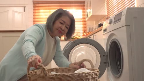 Woman Removing Laundry From Washing Machine in Bright Kitchen