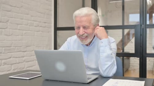 Senior Businessman Chatting Online on Laptop while Sitting in Office