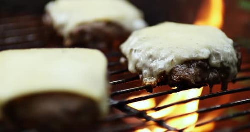 Close up of juicy cheeseburgers cooking on a grill.