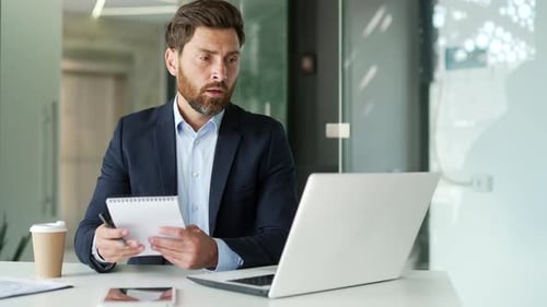 Bearded Man Attends Video Call in Modern Office