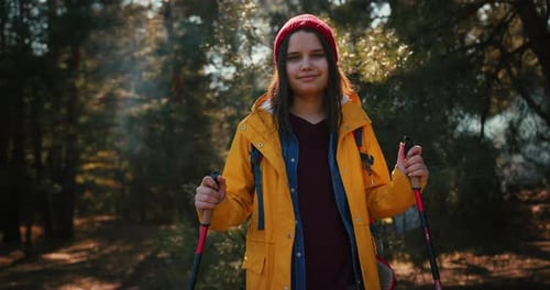 Backpacker Hiker Girl with Hiking Poles Walking Between Trees in a Mountain Forest Hispanic Teenager