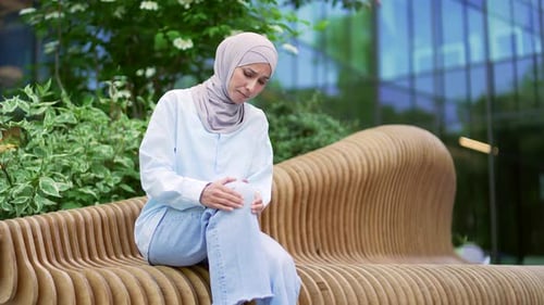 Adult Woman Massaging Knee While Sitting Outdoors