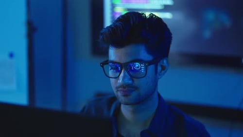 Auf Programmierer fokussierter Softwareentwickler, der spät in einem dunklen Büro arbeitet.