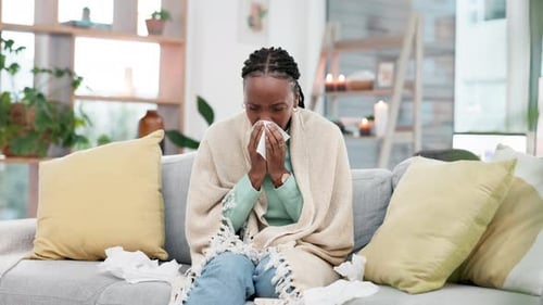 Woman Blowing Nose with Tissues While Sitting Indoors