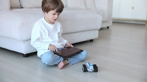 Child Playing on Tablet with Toy Car at Home
