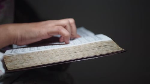 Nahaufnahme einer Hand, die Seiten in einem alten Buch umblättert