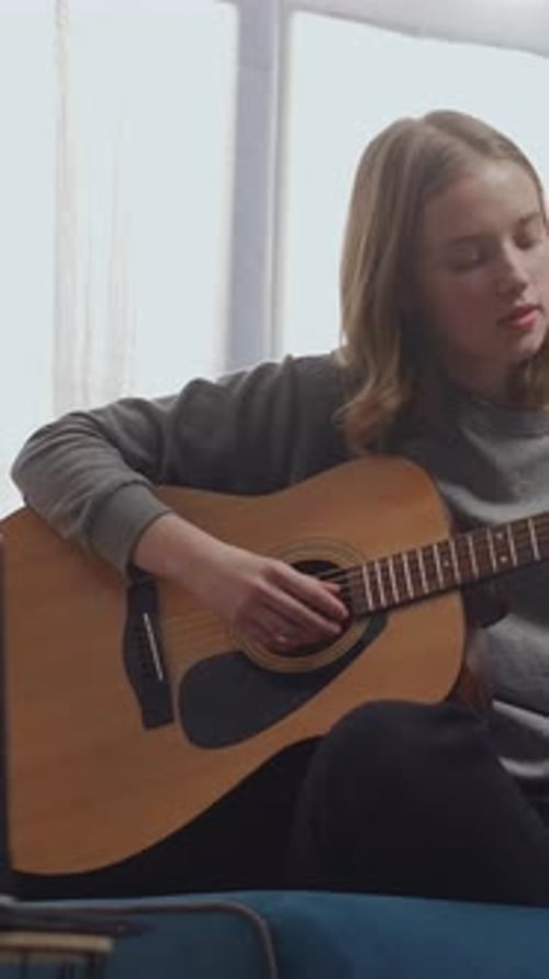 Teen Girl Practices Guitar, Plays Instrument at Home