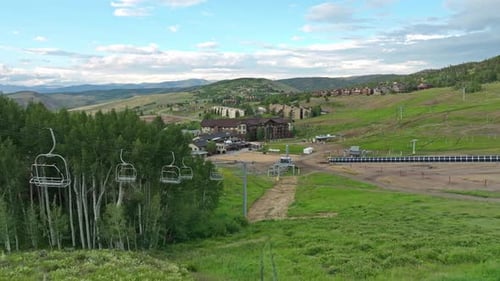Aerial dolly over ski chair lift next to lush green trees in high alpine of Colorado in the summer