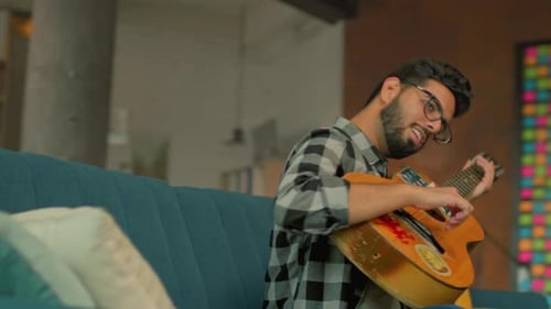 Casual Musician Creating Melodies at Home Studio Asian Man with Plaid Shirt Playing Guitar in Sunlit