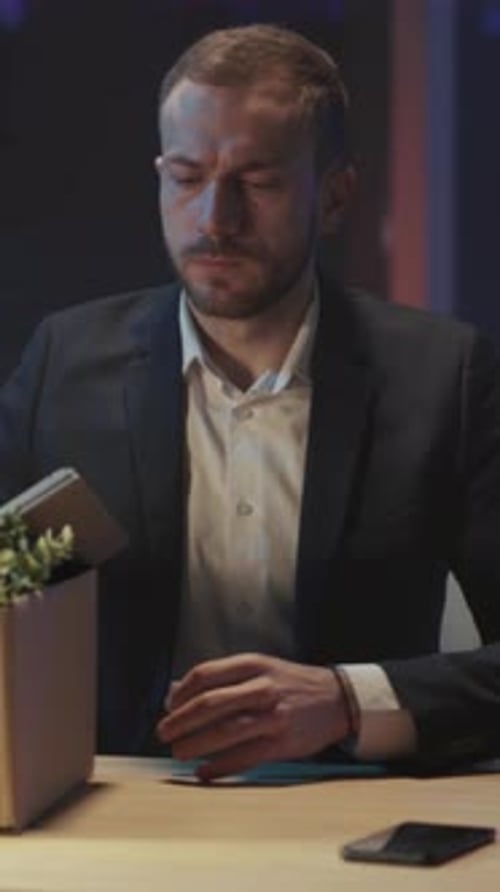 Fired Man Packing Belongings in Box at Night