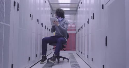 Ingénieur informatique ou spécialiste de la science des données travaillant sur une tablette dans une salle de serveurs dans un cloud moderne