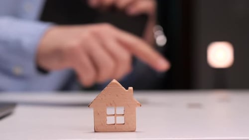 Businessman Counting Money with Wooden House on Desk Representing Real Estate Investment