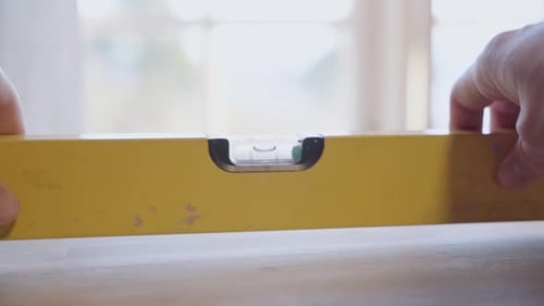 Close-up of a spirit level, person checking if a table is properly leveled.
