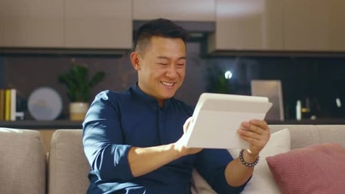 Happy Adult Using Tablet on Sofa at Home