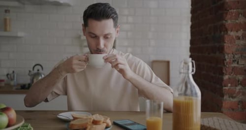 Young Adult Using Phone and Drinking Coffee