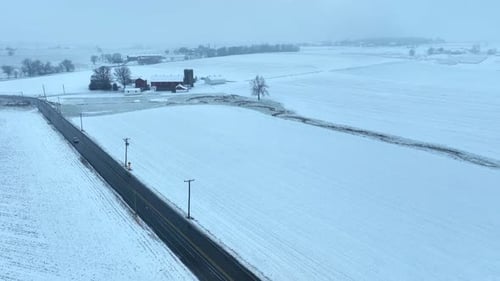 Aerial shot of rural USA. Snow covered farmland with farms, meadows, and countryside.