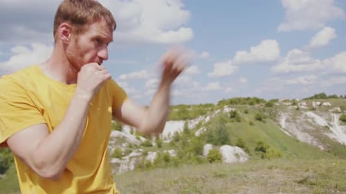 Man Practicing Boxing Moves in Scenic Park on a Sunny Afternoon