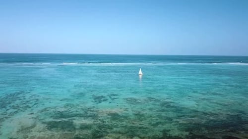 Wonderful aerial flight slowly rise up drone shot of chasing a sailboat with white sails
on reef Par