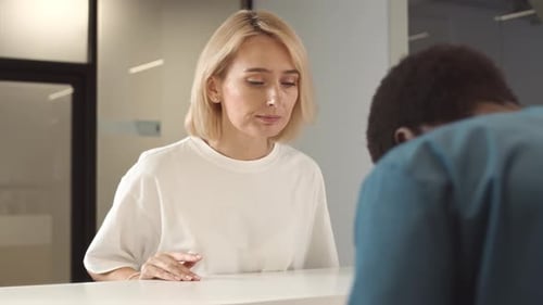 Woman Talking to Male Nurse at Reception Desk in Clinic