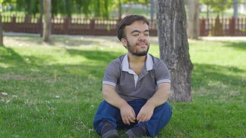 Man Sitting on Grass in a City Park