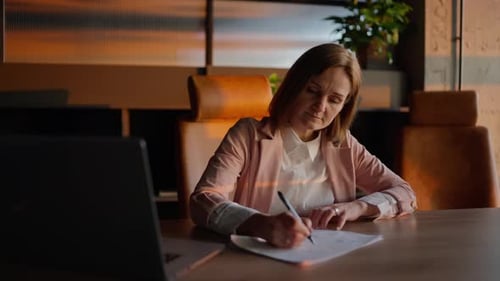 Woman Writes at Conference Table in Golden Light